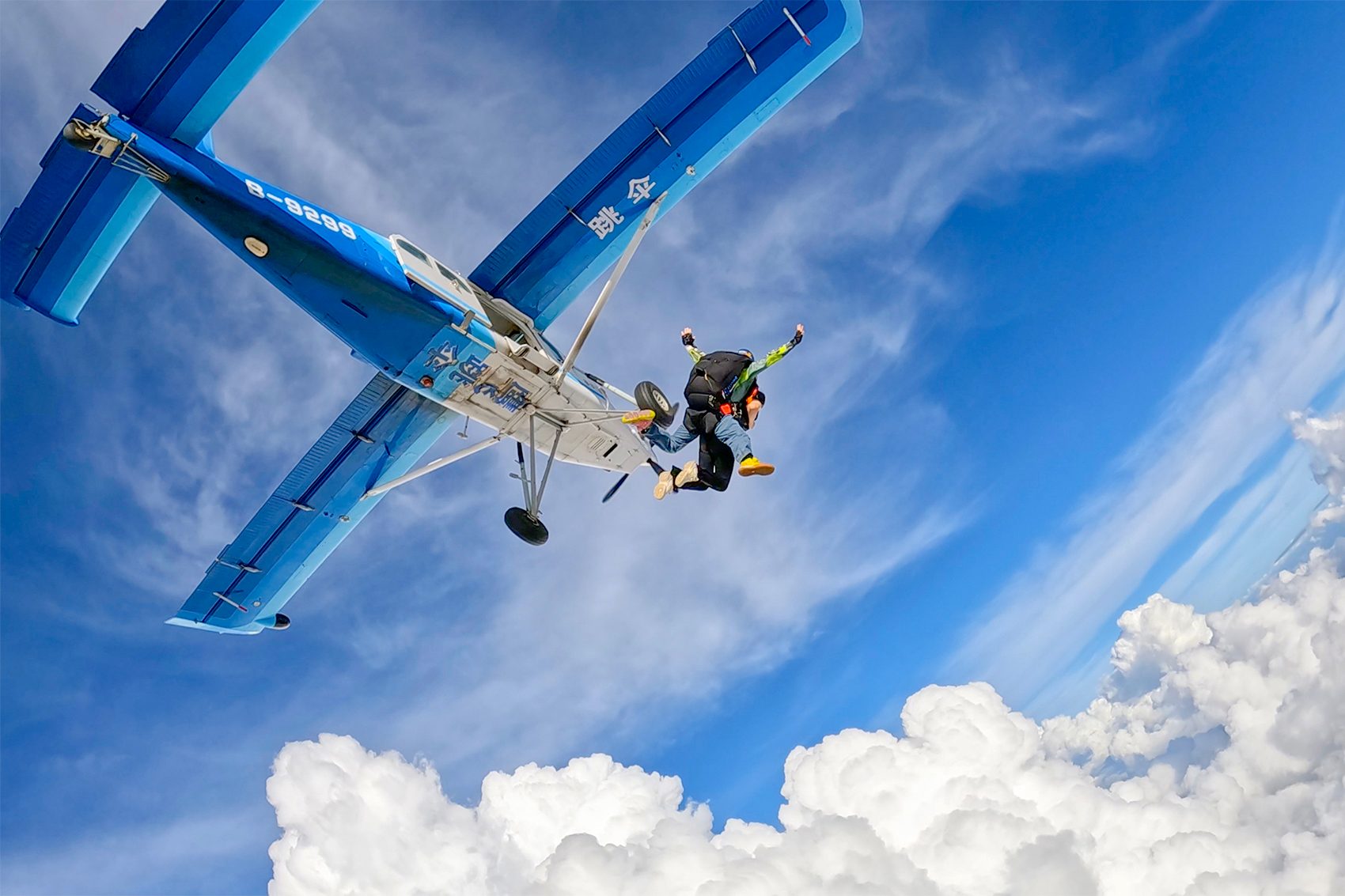 Two skydivers jumping out of a plane high up in the sky. 